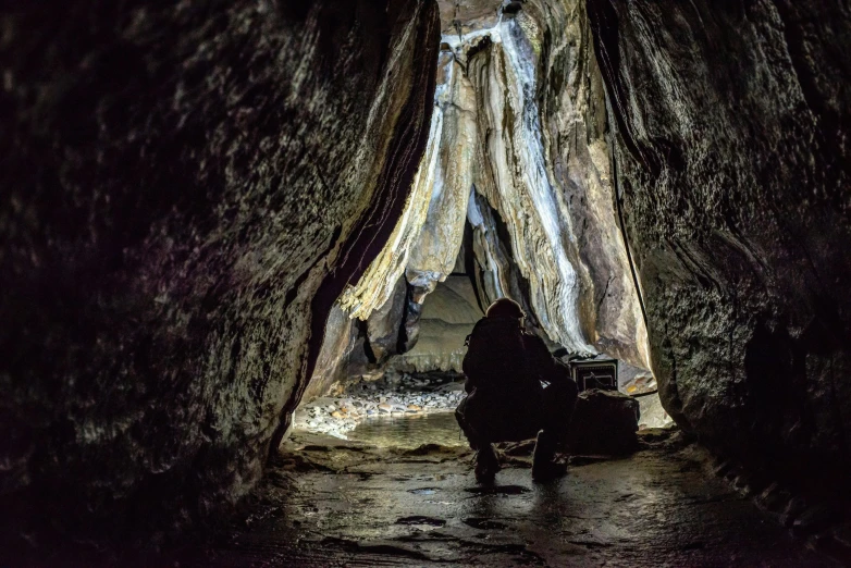 person sitting in a cave with a backpack and backpack