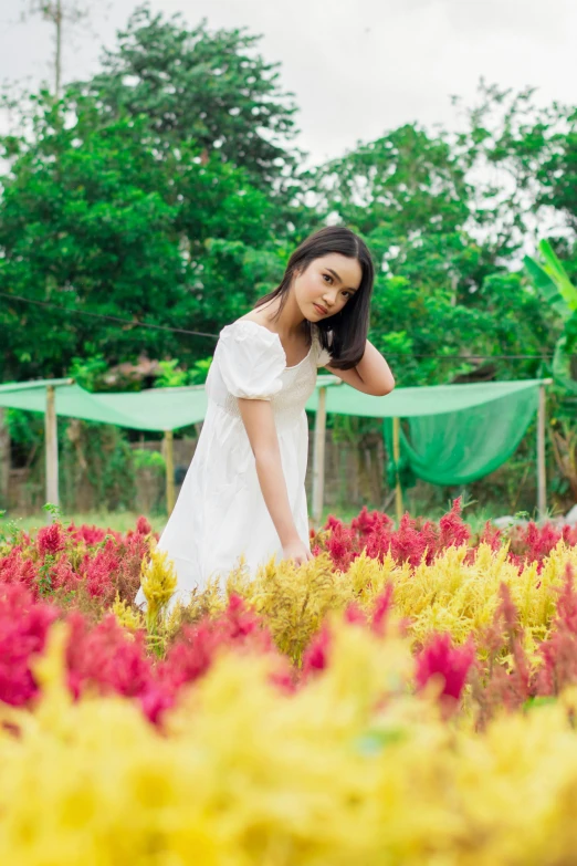 a girl is standing in a field with many flowers