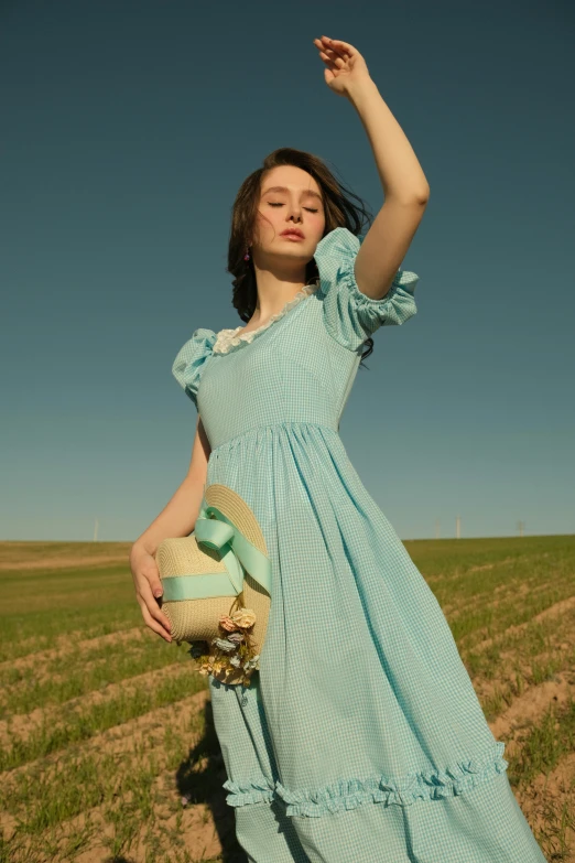 the woman is wearing a long dress in a field