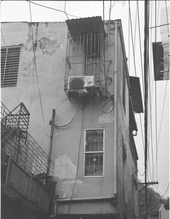 a building with a balcony with cage hanging from it