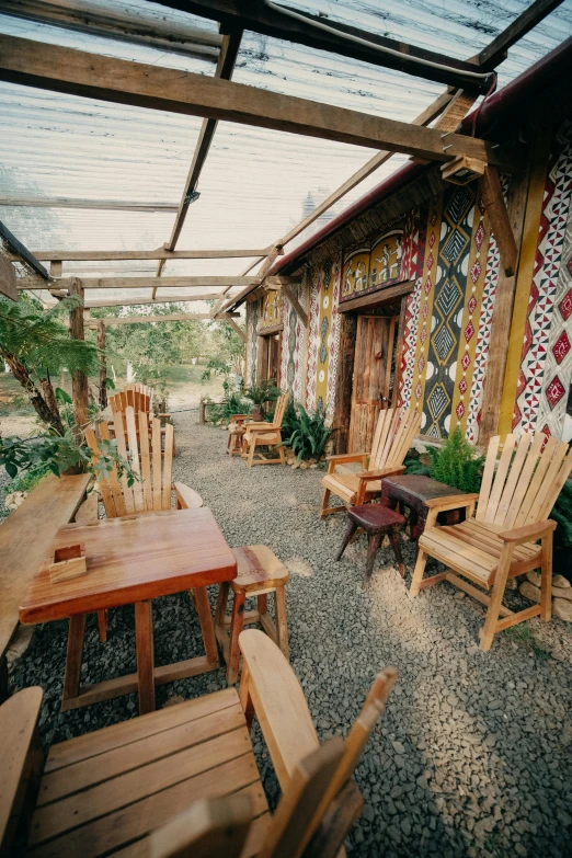 a deck with wooden furniture and chairs on top of gravel