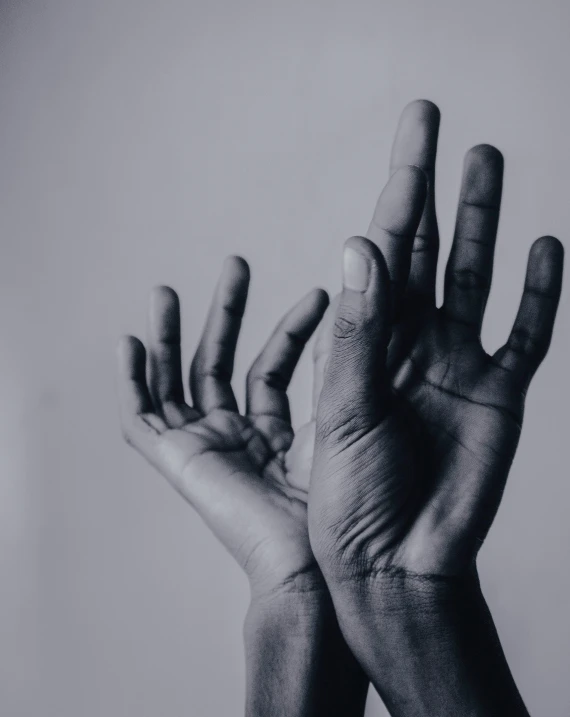 the two hands of a person who is reaching out their fingers