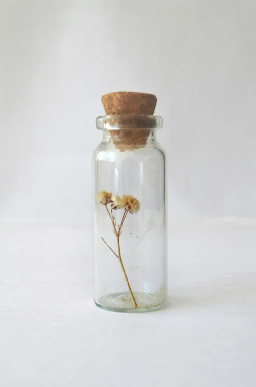 an unlit bottle with the bottom full of clear glass and flowers inside