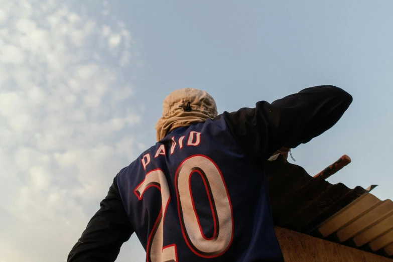 a man in a jersey looking at a kite