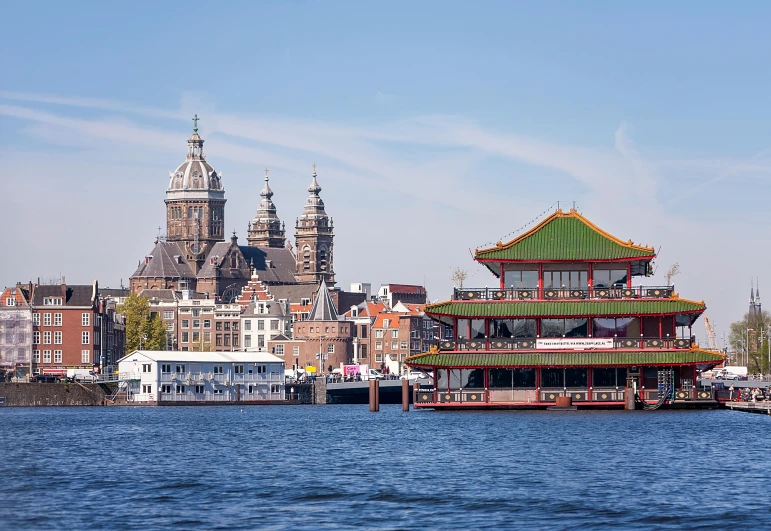 a long building sitting by the water in front of a city