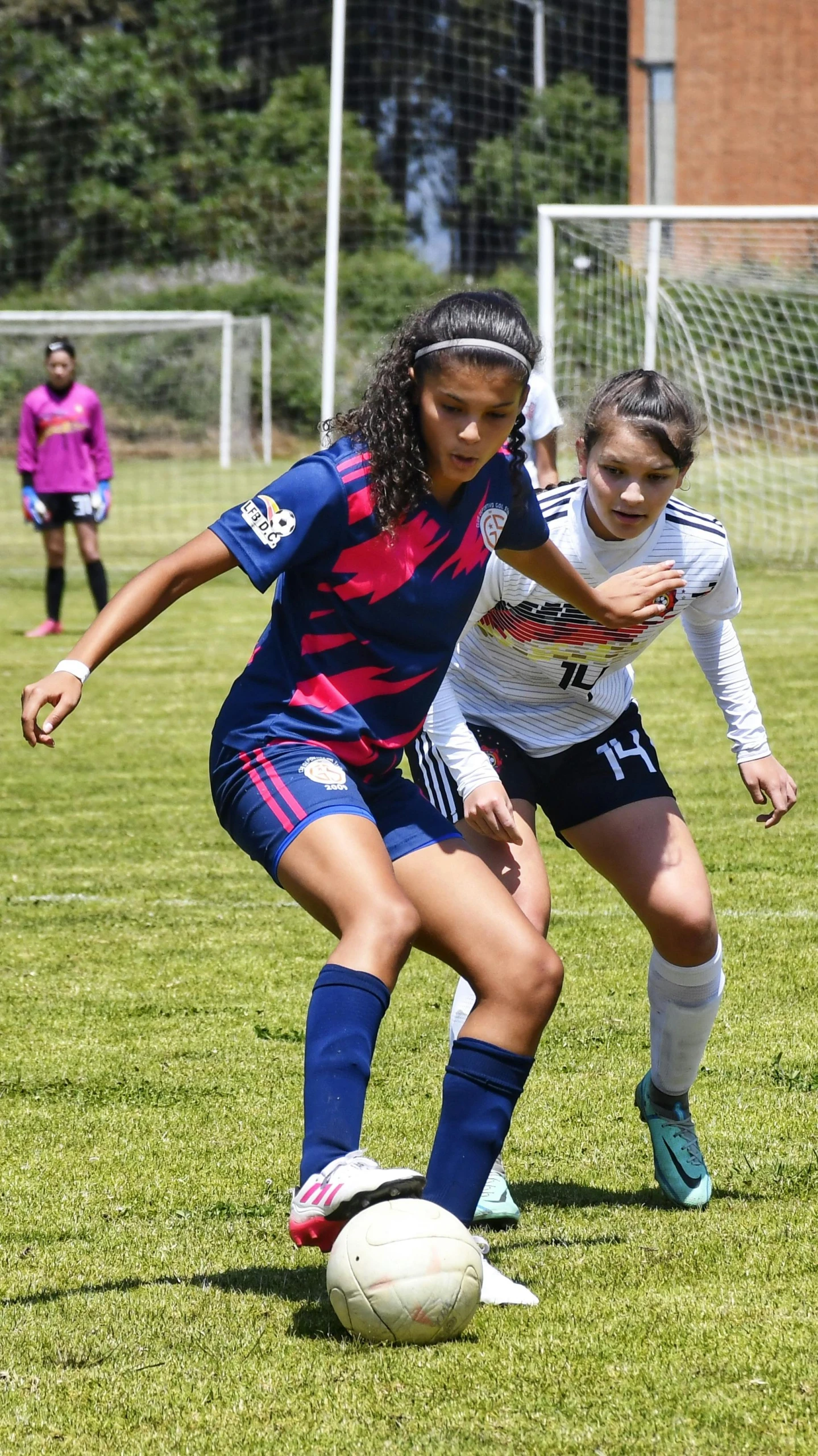 two girls in uniforms playing soccer together