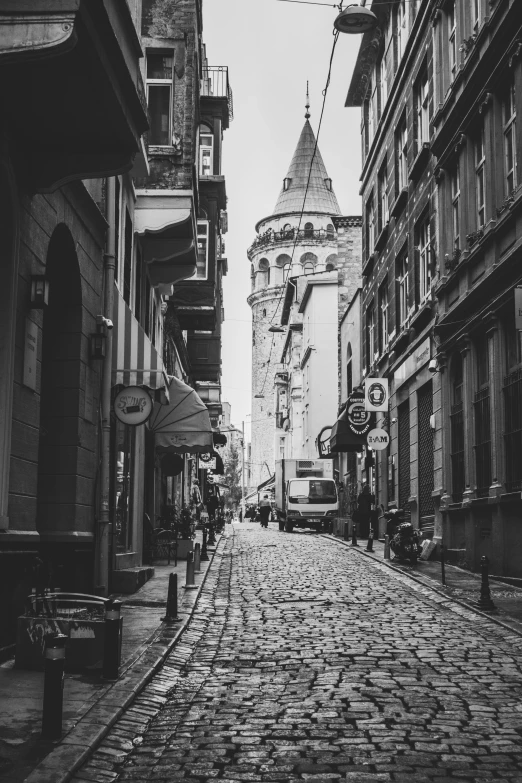 a cobble stone road leading towards a tower on a building