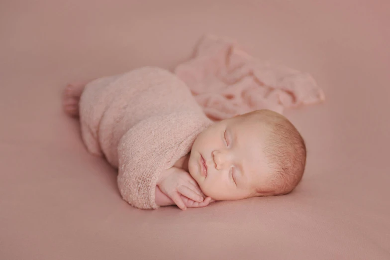 the baby is laying down with his head on a pink blanket