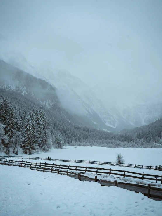 fence in snow with mountains and clouds in the background