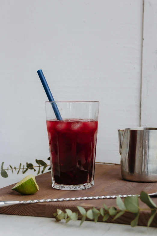 there is a glass with red liquid inside on a tray