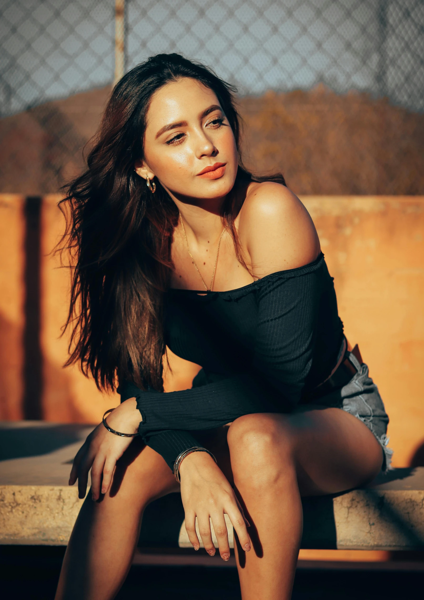 a woman is sitting on a bench wearing an off shoulder black top