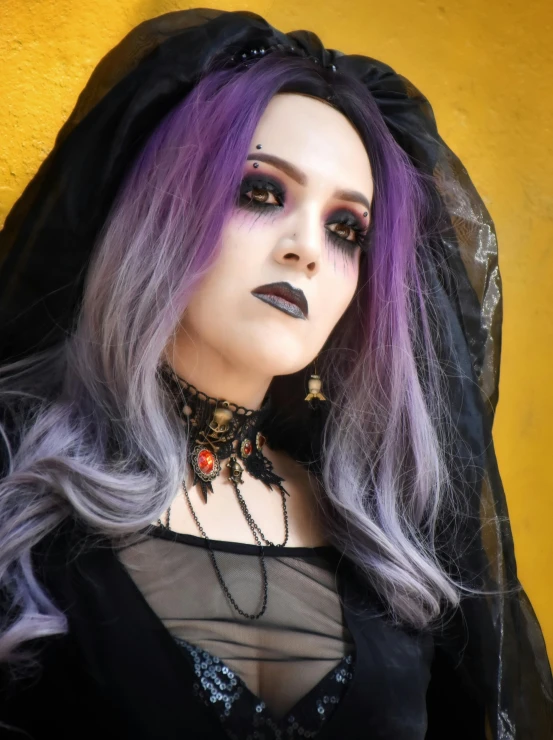 the woman with purple hair is wearing black makeup