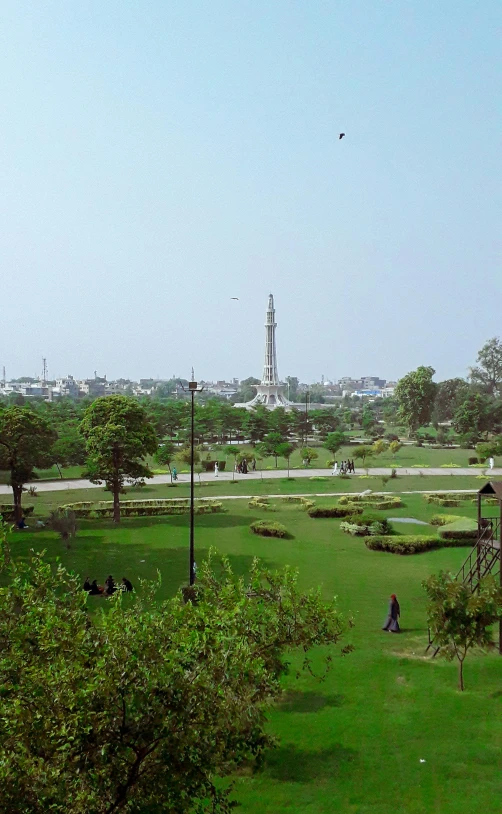 a green area with a few people walking on the grass