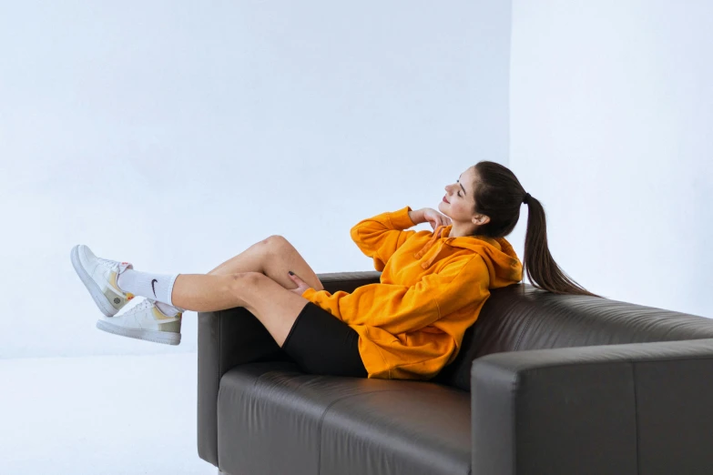 woman wearing a yellow jacket sitting on a brown leather sofa