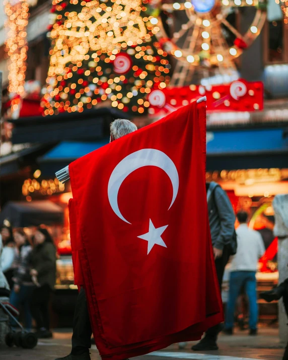 people walk in front of a christmas tree holding an ottoman flag
