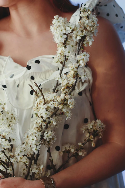 woman in white dress holding flowers with dotted dots around neck