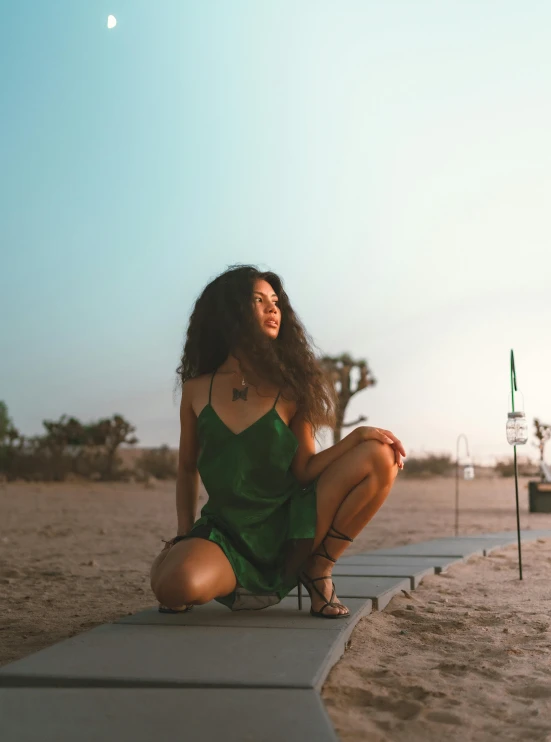 the woman in the green dress is sitting on a platform