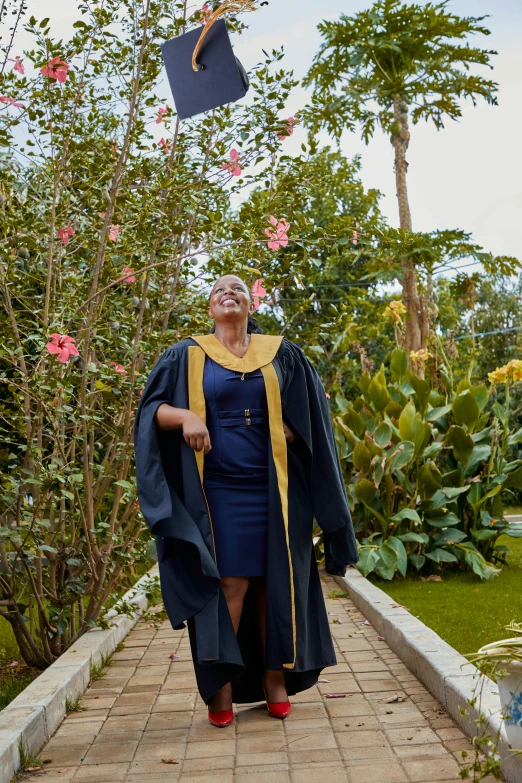 old woman in graduation gown throwing up a black mortar