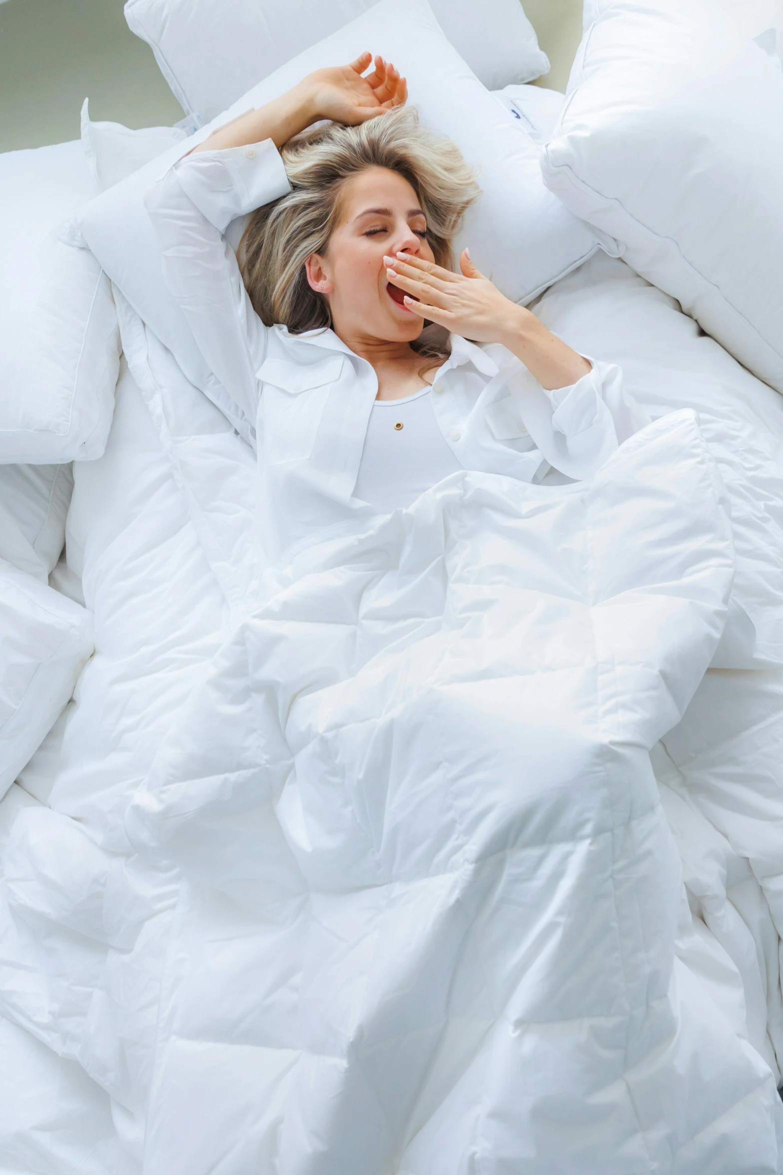 a woman sleeping on her back in bed with pillows