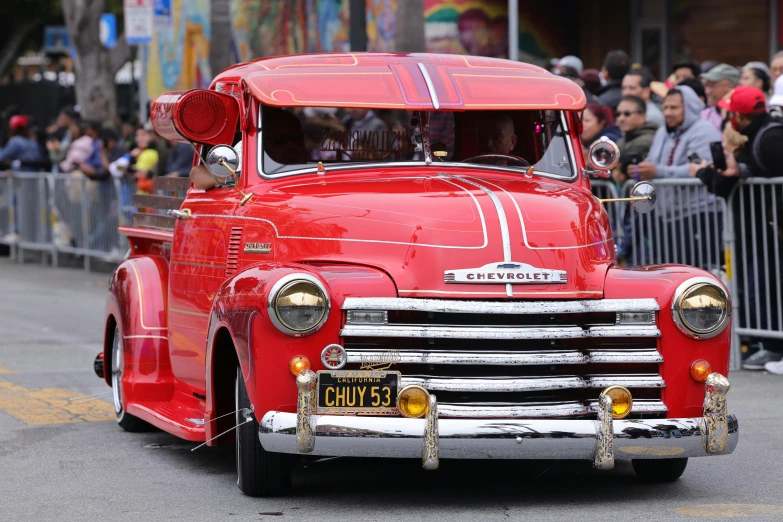 a red truck driving down the street with many people