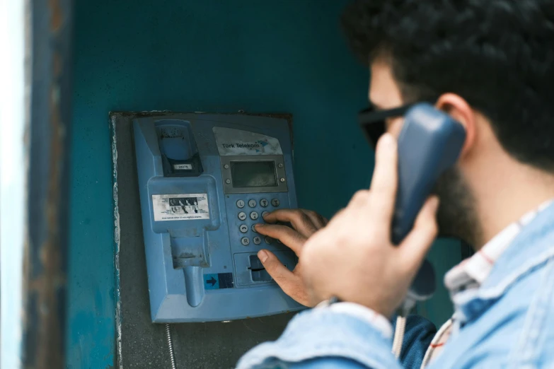 a man with sunglasses on a phone dialing the number of an atm