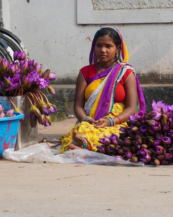 a woman selling purple flowers in a market place