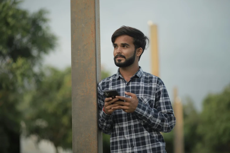 a man is looking at his cell phone while holding it up