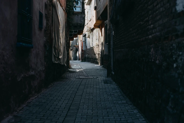 a narrow alley with an empty sidewalk surrounded by brick buildings