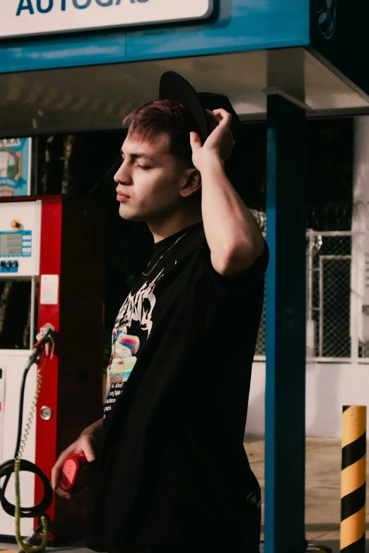 man stands at a gas pump talking on the phone