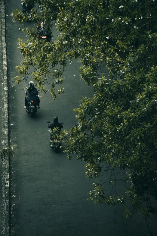 two people riding motorcycles on an empty street