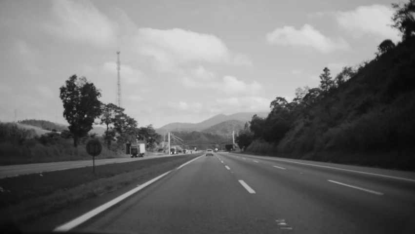 the road is lined with trees and hills