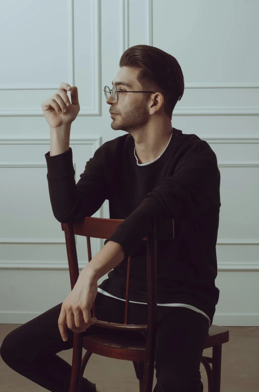 a young man smoking a cigarette sitting in a chair