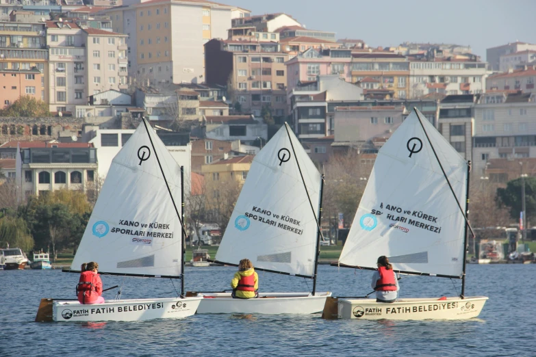 three small sailboats with one sailboat on a body of water