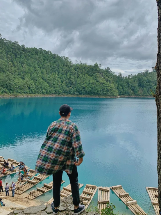 man wearing a plaid shirt stands on the edge of an old dock