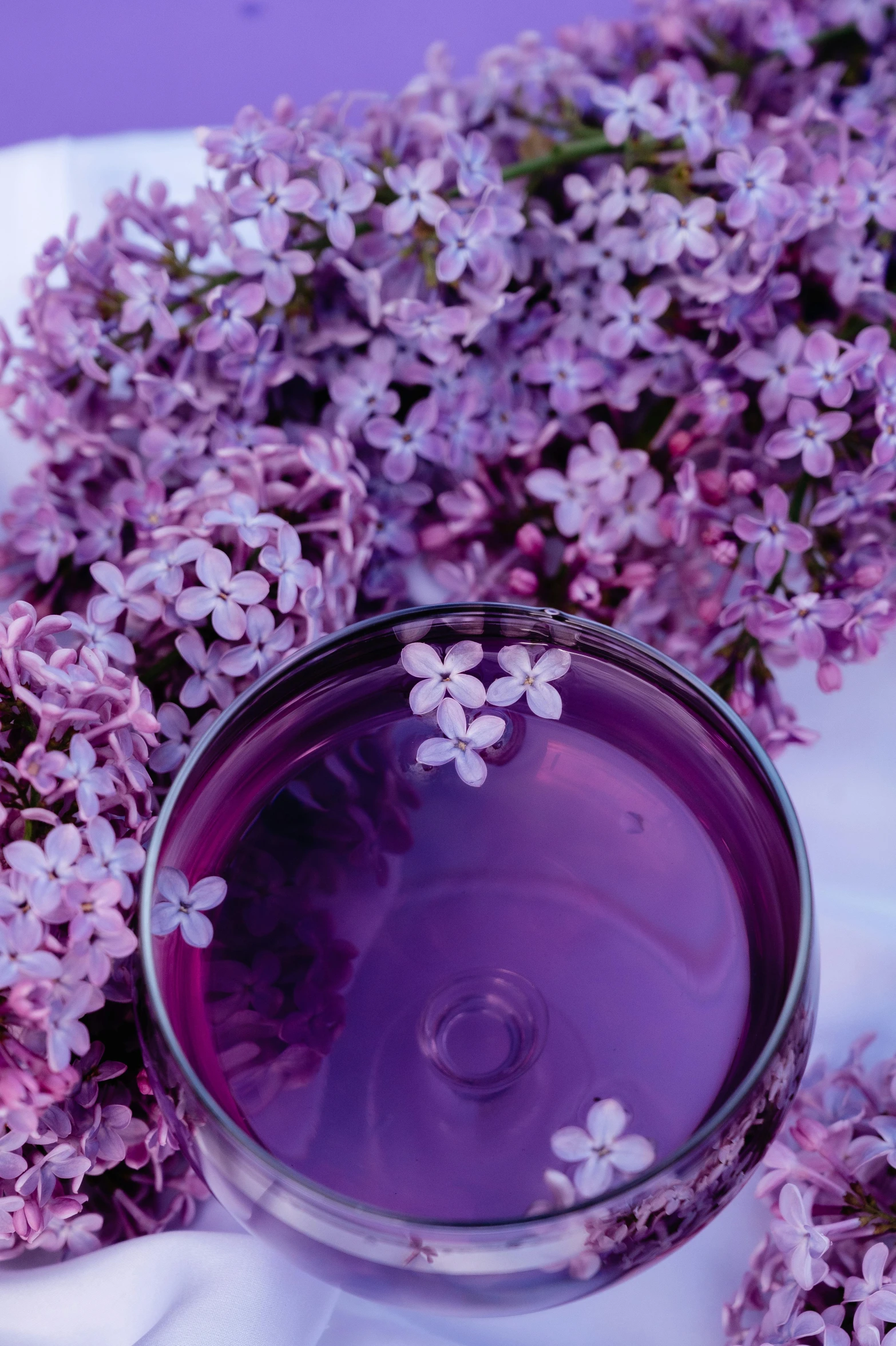 some flowers are in a glass on top of a cloth