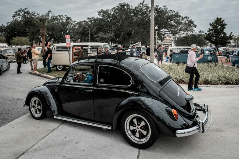 a bug car is parked near a crowd of people on the street