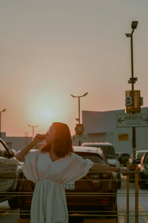 the sun sets behind the woman in a white shirt
