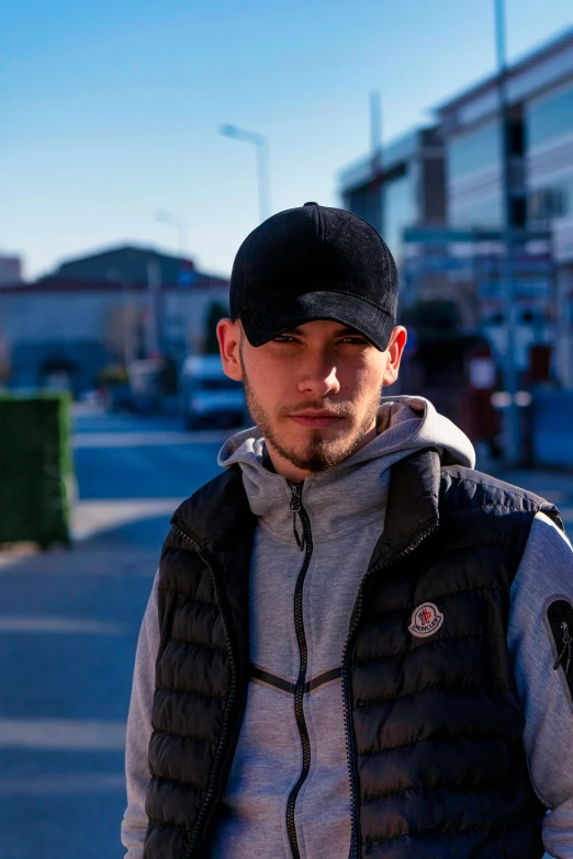 a man with a jacket and hat standing on the sidewalk