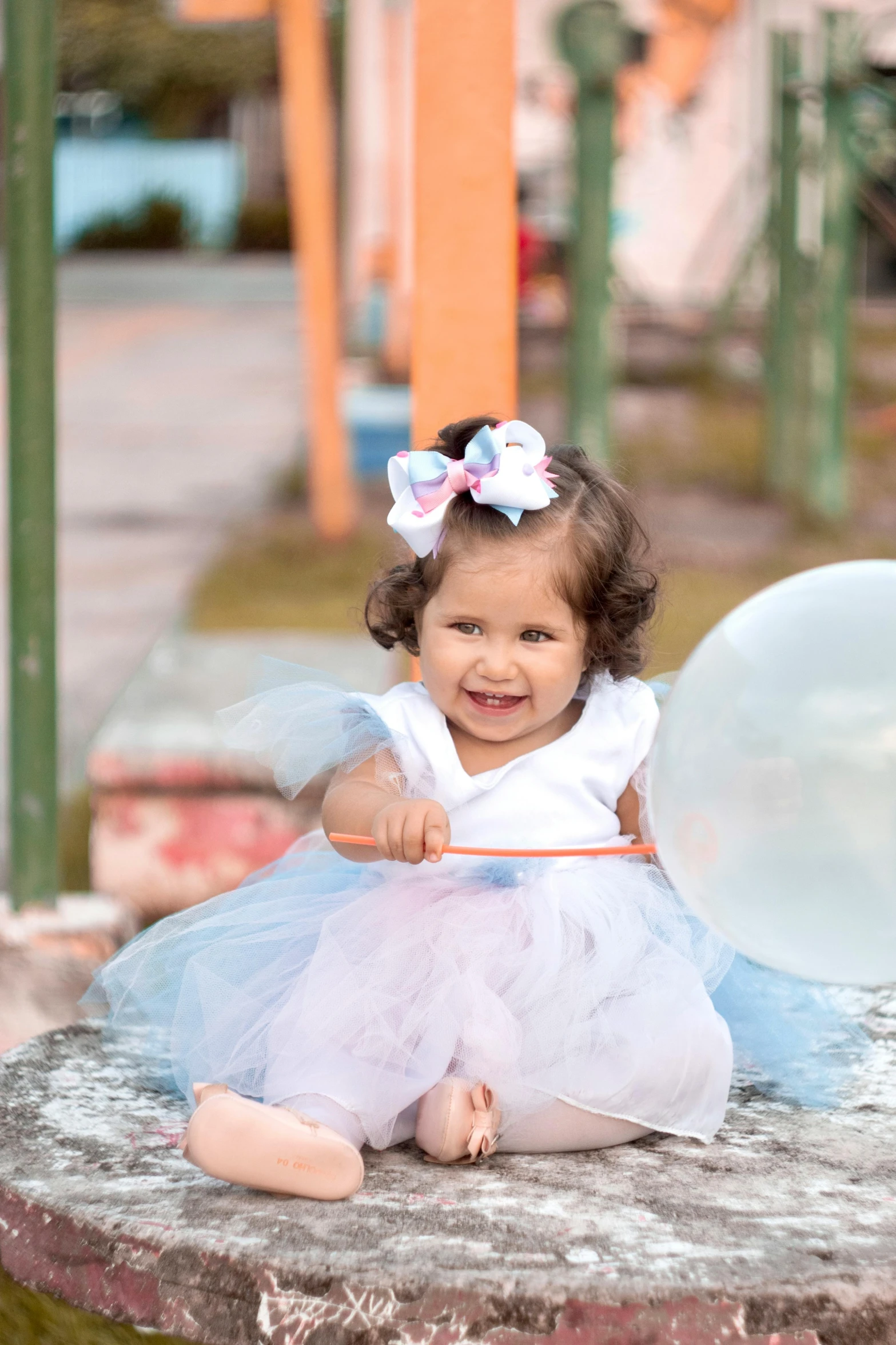 the baby girl is sitting on a small concrete structure