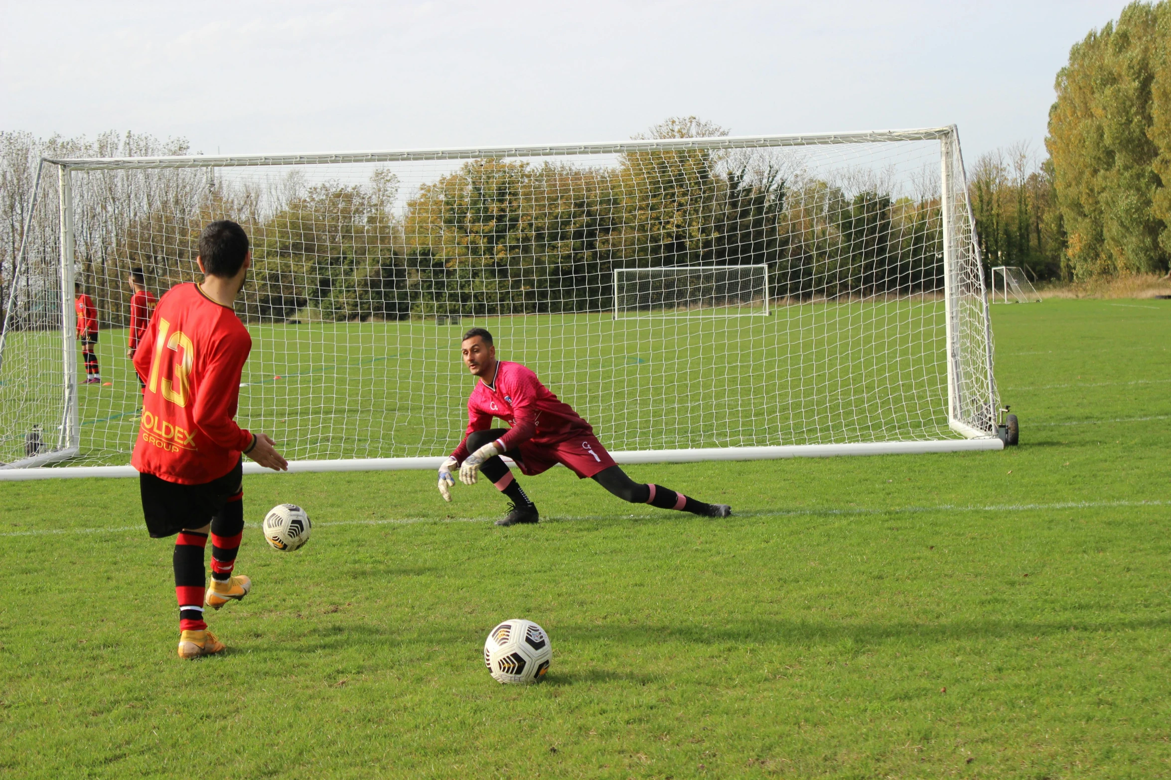 a soccer goalie watches a player about to kick a ball