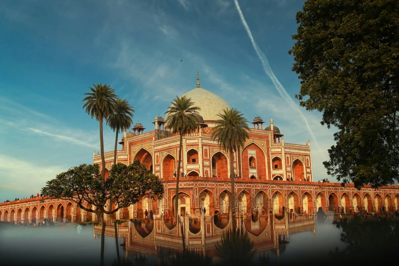 an ornate building with palm trees in front and water in the foreground