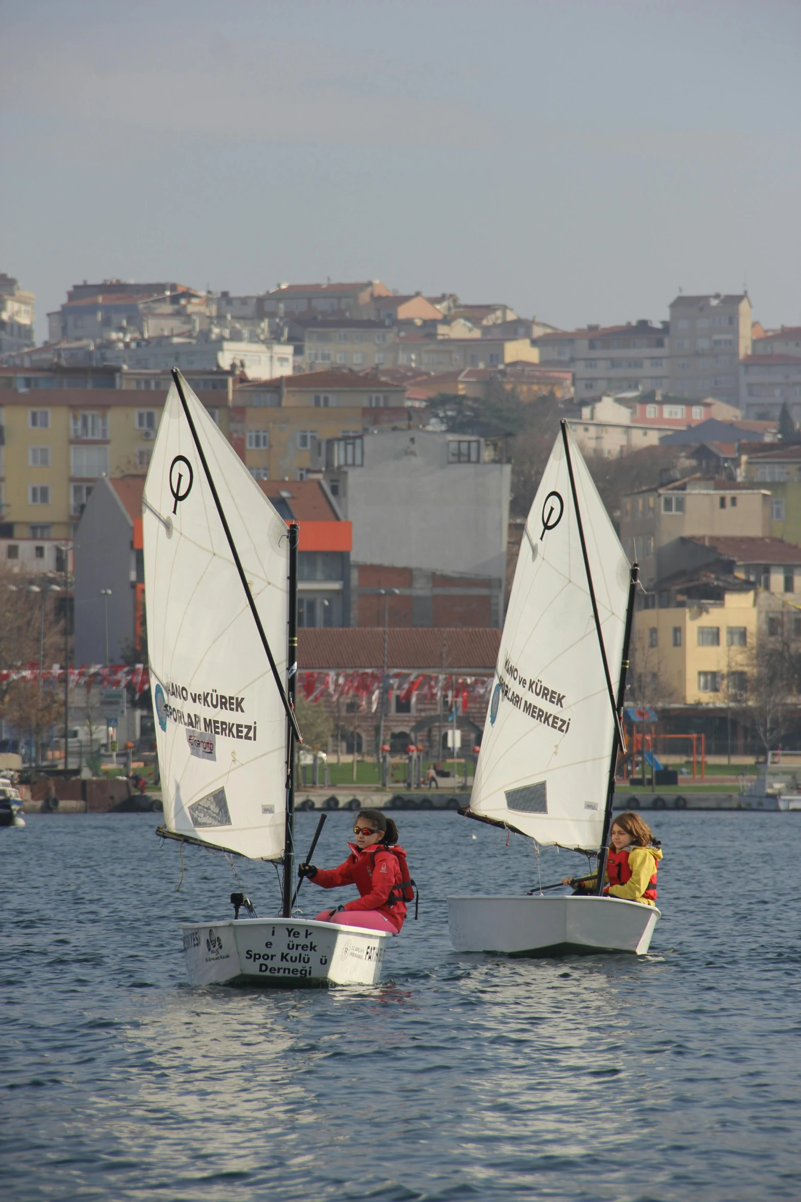 two people on small sailboats in a harbor