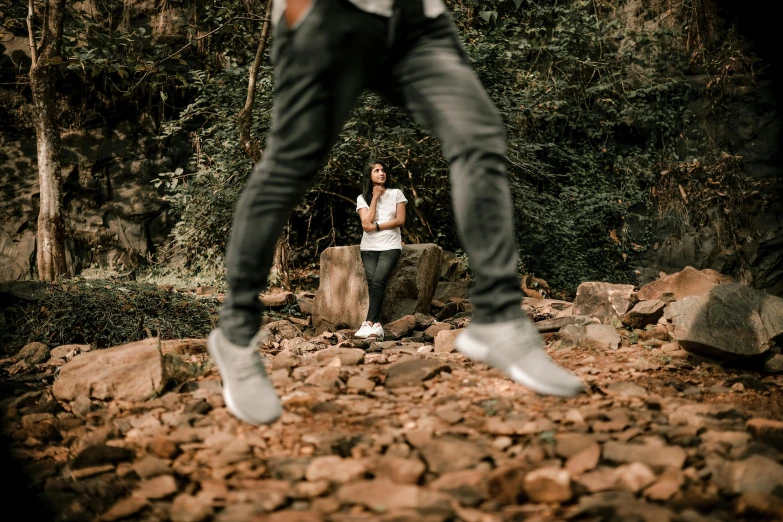 a man is standing on a rock wall by trees