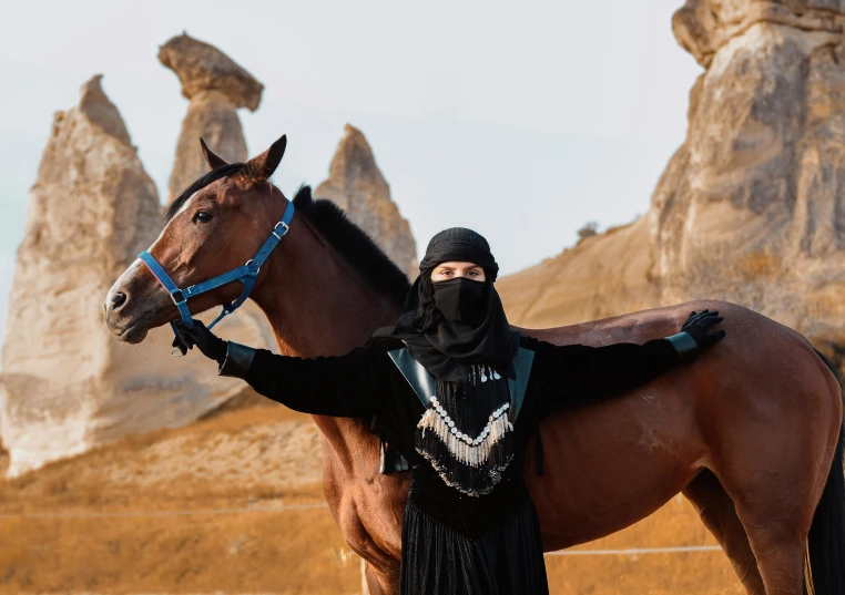 a woman posing with her horse outside in a desert setting