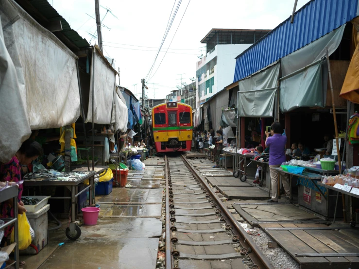 a train traveling down tracks past a market and shops