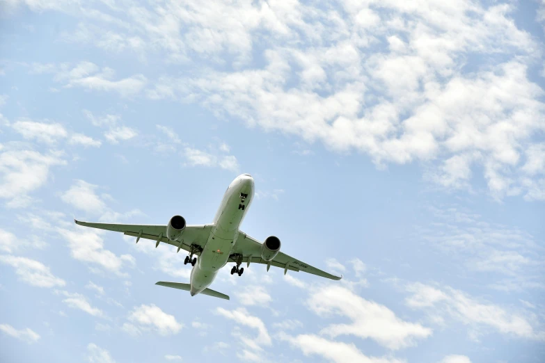 an airplane flying high in the blue sky with a small landing gear down