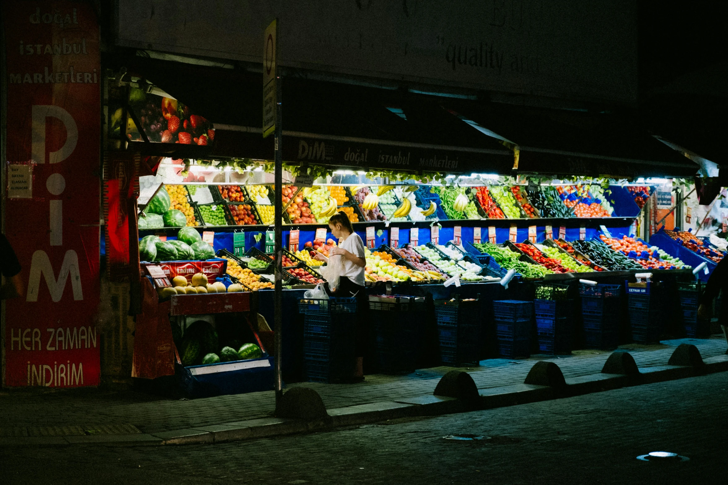 an open air fruit and vegetable market with people walking by