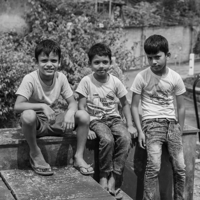 three young children sit and look forward in black and white