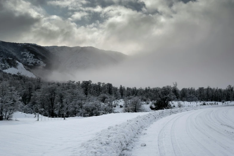 road in snow with trees and mountains on either side