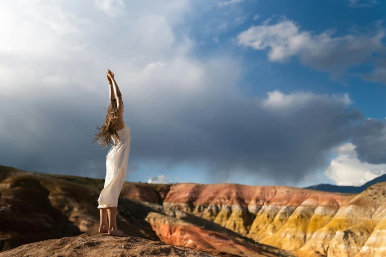 a woman is standing on the edge of a hill